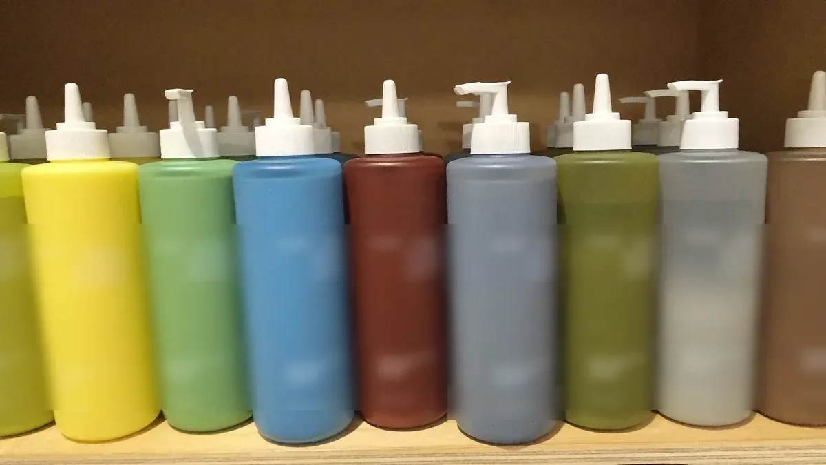 Unlabeled paint bottles beside an airbrush